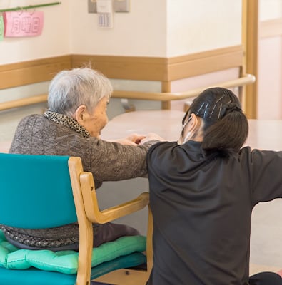 介護職員が高齢者の肩に手を置いてコミュニケーションを取っている様子